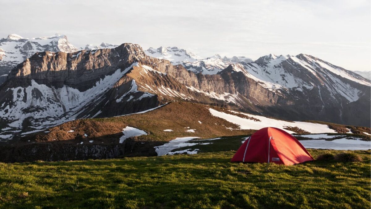 A tent pitched in front of snow-capped mountains
