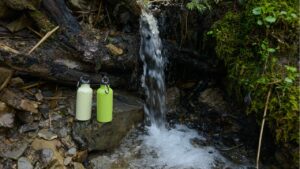 Two Hydro Flask bottles next to a waterfall